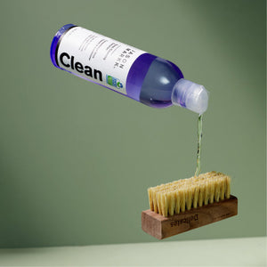 Cleaning solution pouring onto a delicates brush in front of a green backdrop
