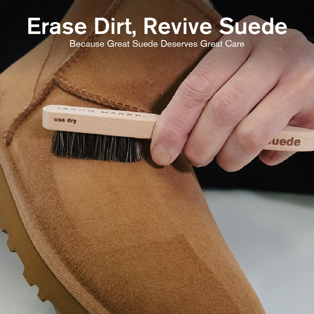 Close-up of hand using Jason Markk suede cleaning brush to remove dirt from a suede boot. Text reads “Erase Dirt, Revive Suede.” Dry-use brush designed to clean and restore suede and nubuck, lifting dirt and refreshing texture for effective, gentle shoe care.
